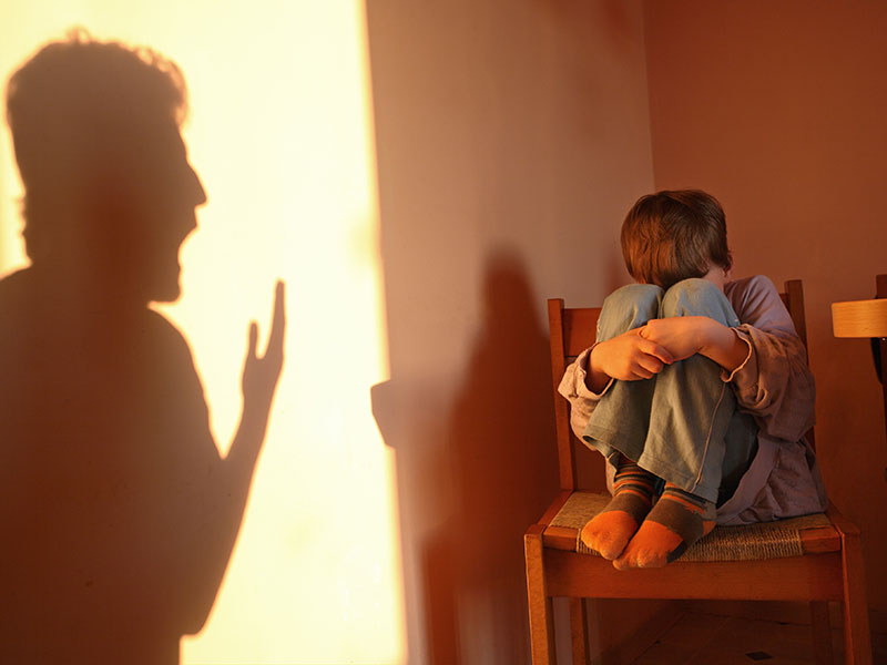 A parent/carer yelling aggressively at a cowering child