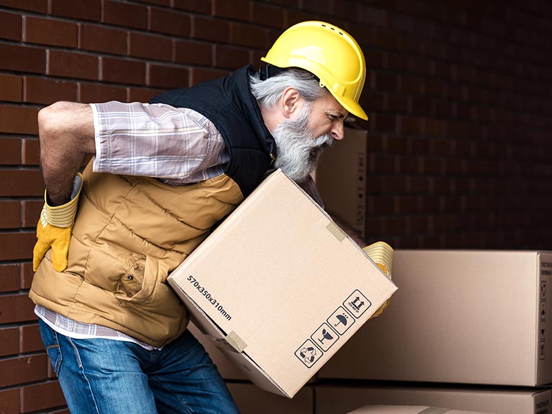 A man with back pain lifting a box