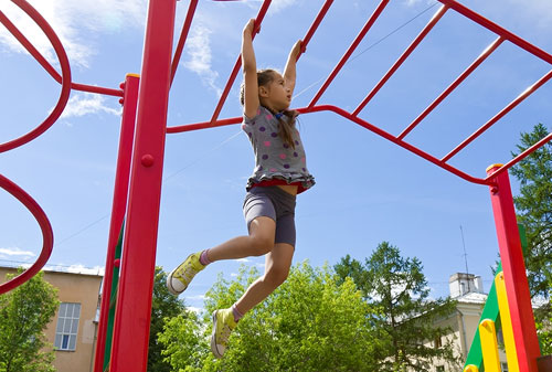 A child swinging from bars in the playground