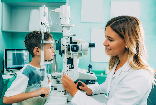 Side view of female ophthalmologist checking eyesight of boy in hospital