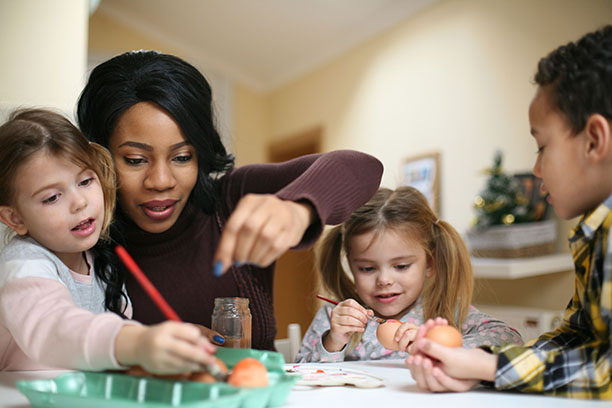 A social care worker painting eggs with young children