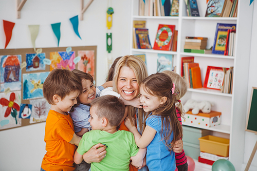 A nursery nurse being hugged by children