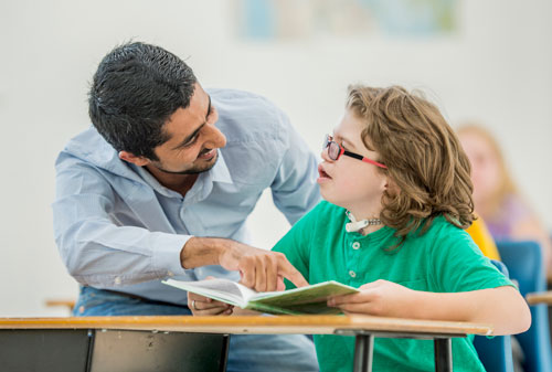 Girl doing school work with help from a teacher