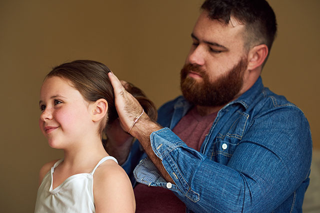 Father brushing daughter's hair