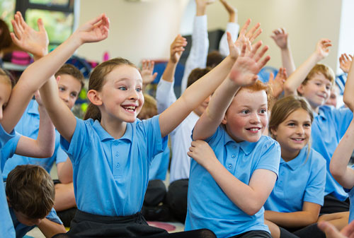 Schoolchildren raising their hands to answer a question